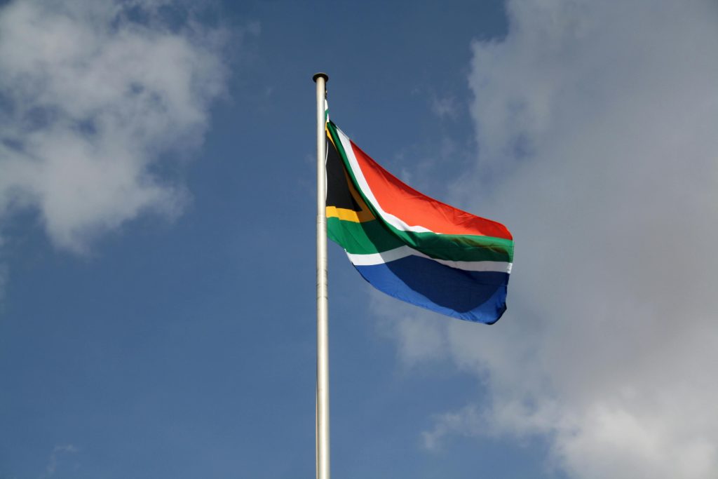 Vibrant South African flag waving proudly against a blue sky with clouds.